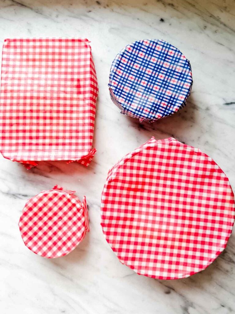 Food containers are covered with beeswax food wraps made of checkered and plaid 100 percent cotton shirts.