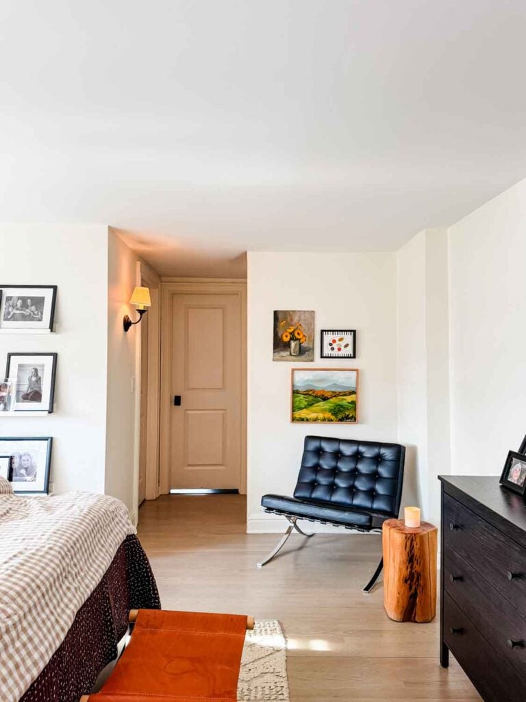 Black leather Barcelona chair, gallery wall, tree stump with candle.