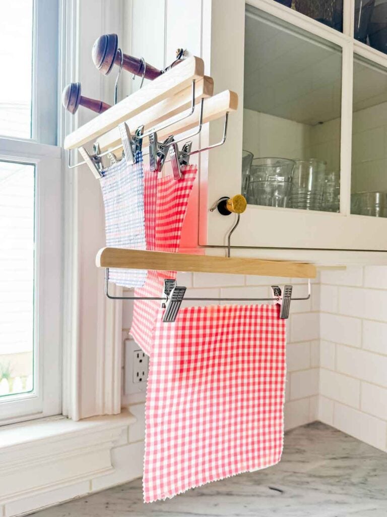 Beeswax-coated fabric is hanging to dry above a kitchen counter.