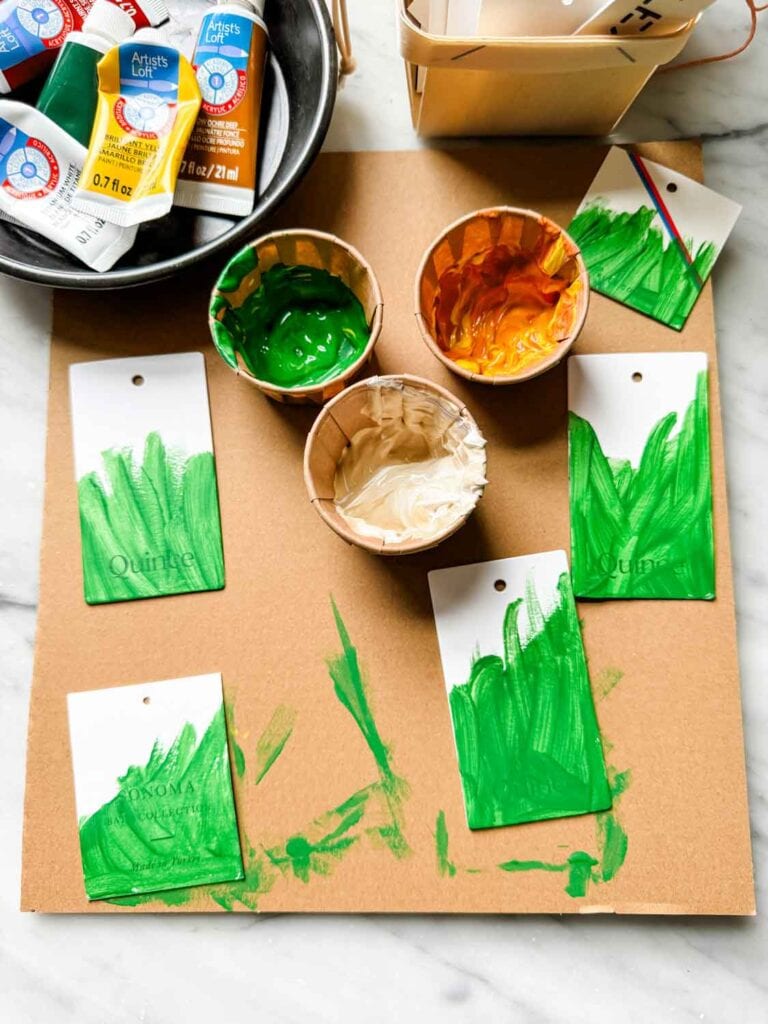 Paints in small cups, paints in tray, tags with some painted green.