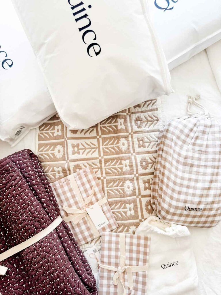 Brown hand-stitched quilt, floral cotton shams, gingham sheets, duvet cover.