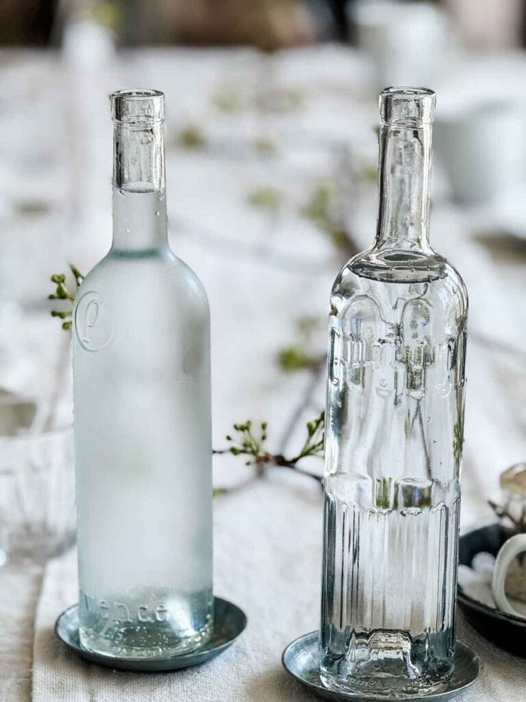 Cold water is served in glass bottles on wine coasters.