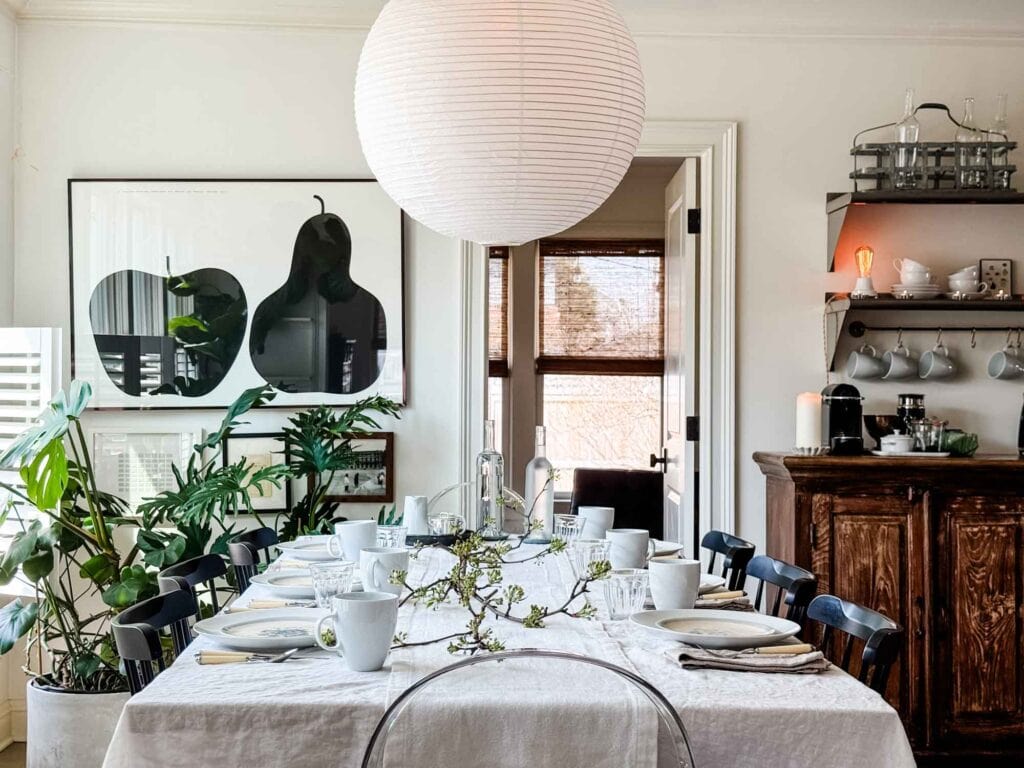 A sprint brunch table is set with a small clipped flowering branch from our yard. A coffe bar is in the background.