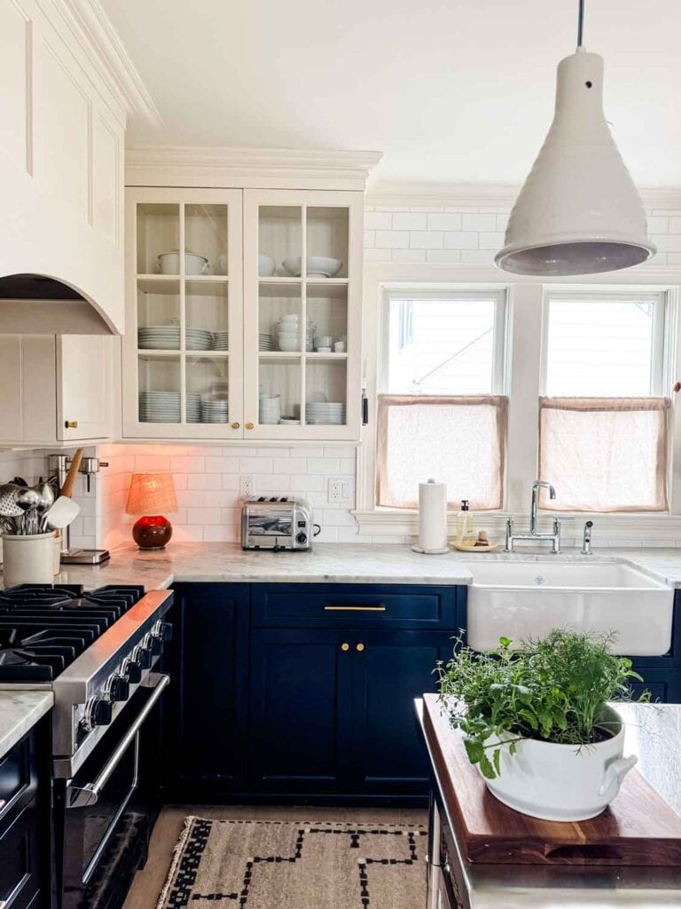 Black base cabinets, white upper, toaster, lamp, farm sink.