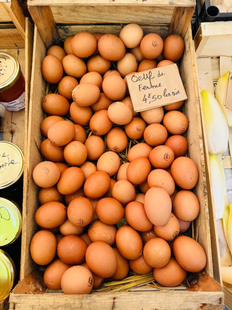 Fresh eggs in a wooden crate with a euro sign are on sale at Marché Raspail.