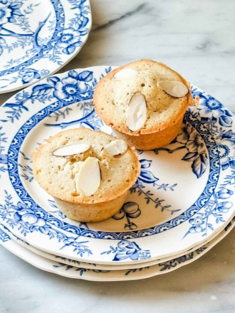 Two classic French financier cakes are served on a blue vintage French plate.