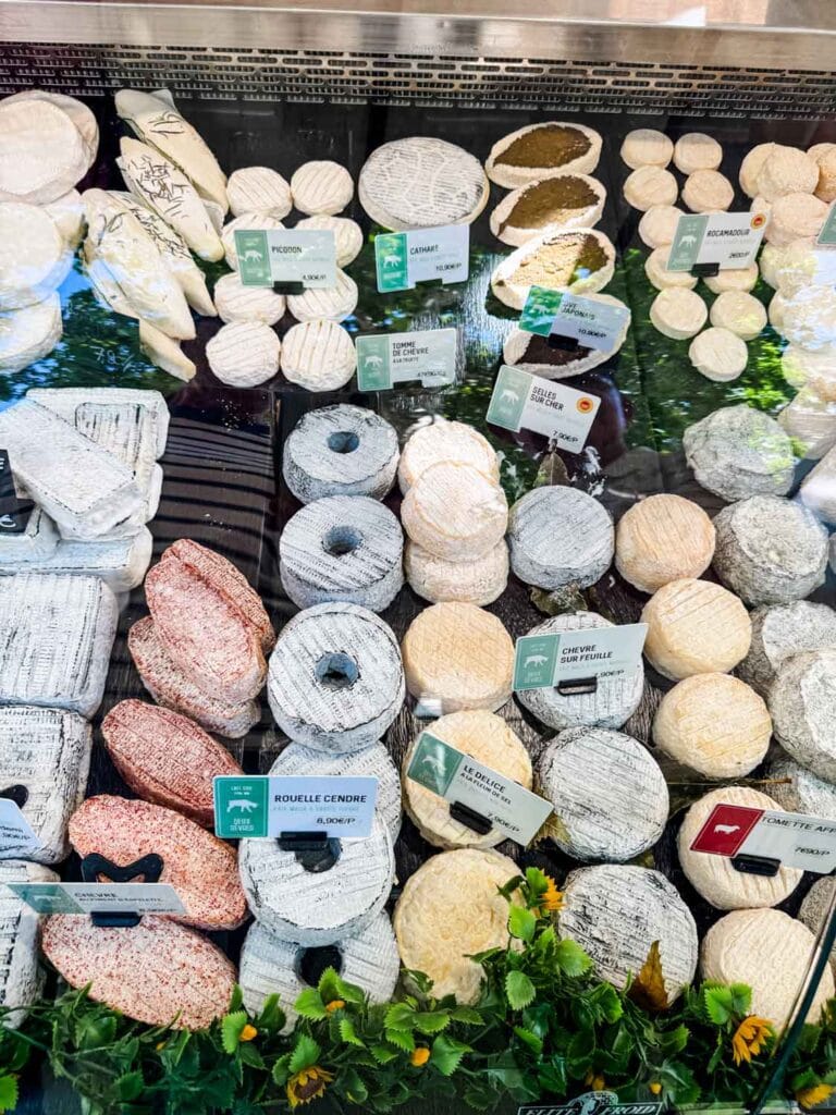 Man varieties of goat cheese are in a cheese counter at Marché Raspail in Paris.