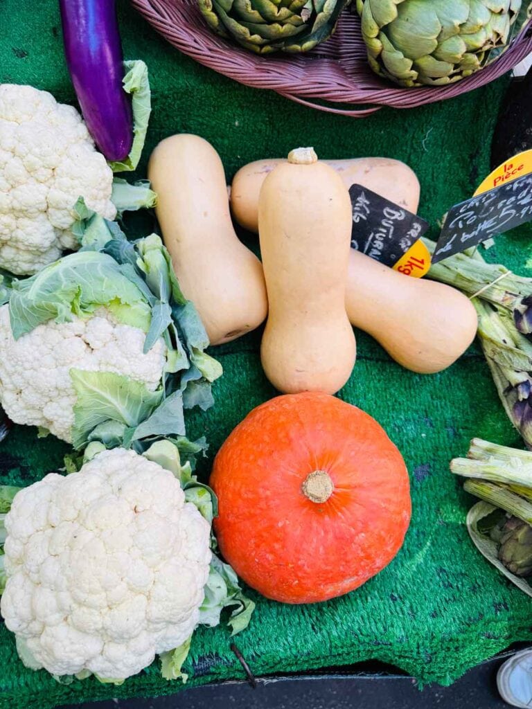 Pumpkin, cauliflower, and summer squash on displayed on a table at Marché Raspail in Paris.