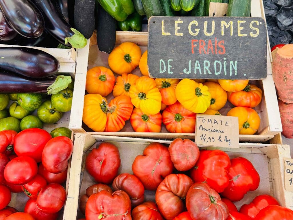 Fresh heirloom tomatoes, eggplant, and other vegetables are on display at Marché Raspail Paris's famous open-air market.