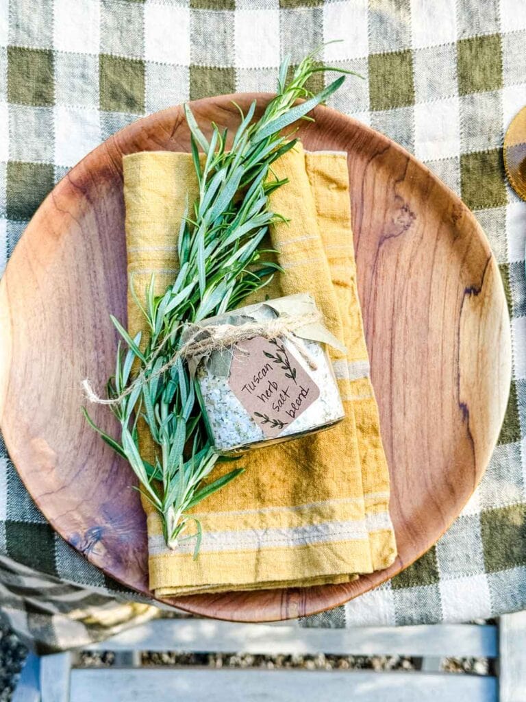 Wooden plate with gold linen napkin and jar of salt and rosemary sprig. 