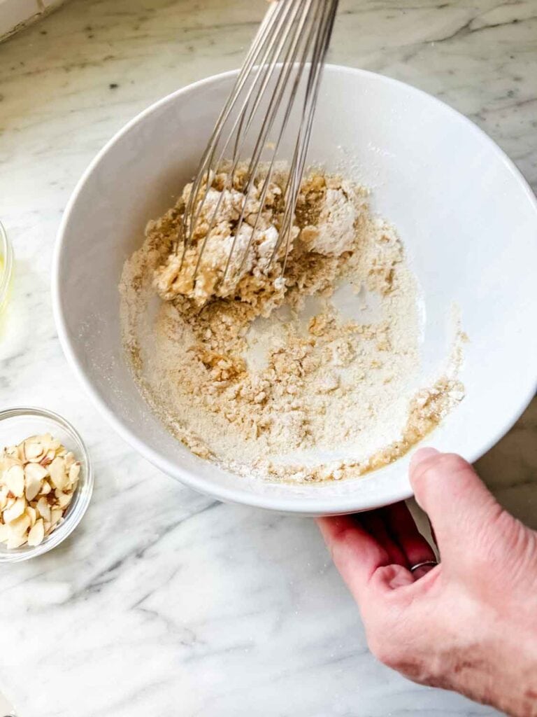 Browned butter and dry ingredients being whisked in a mixing bowl.