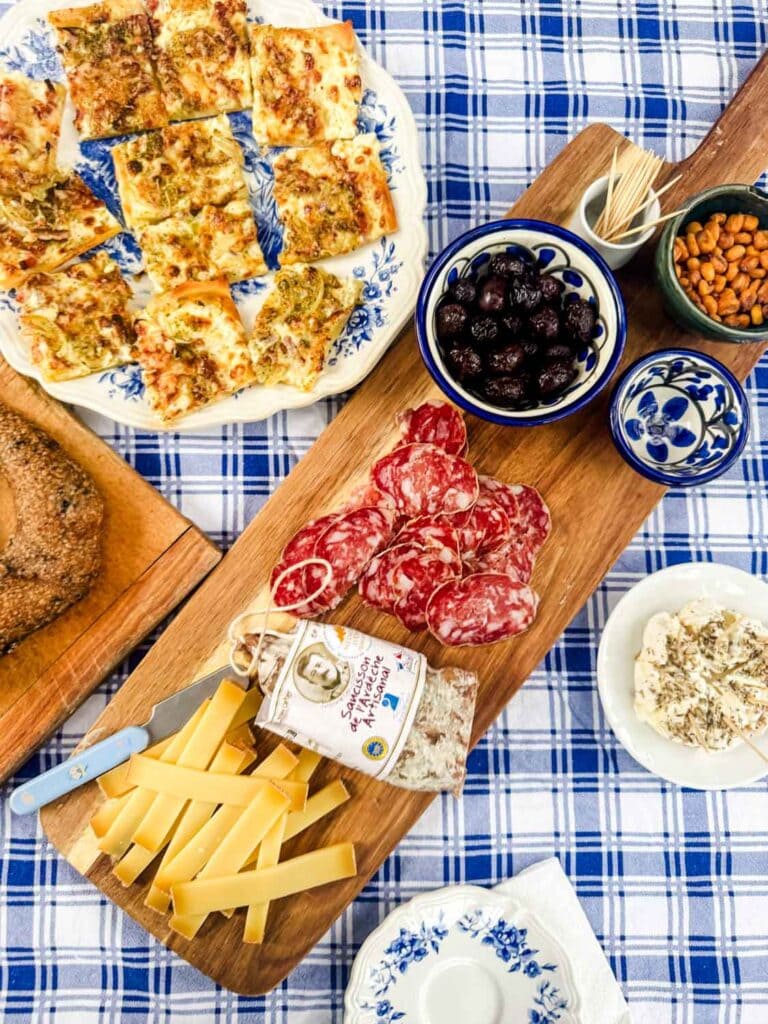 Appetizers on board, plates, on blue plaid cloth.