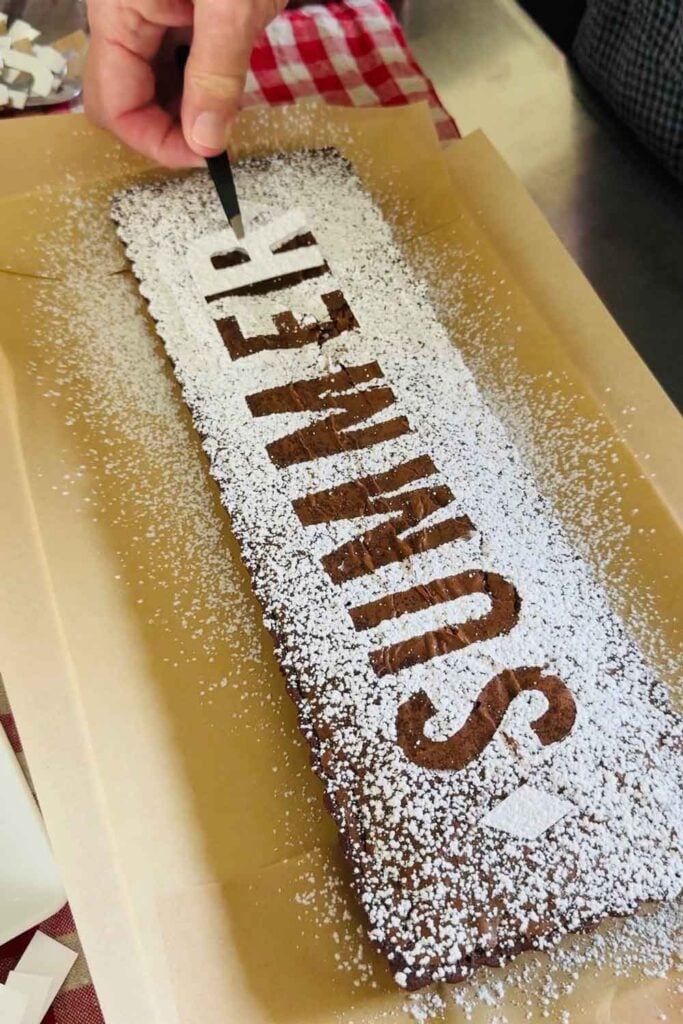 A brownie, dusted with powdered sugar, is decorated with the word summer.