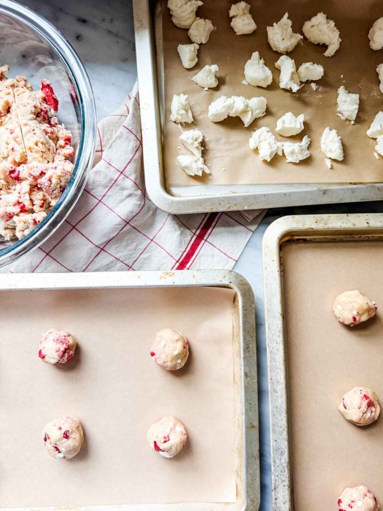 Cookie dough with freeze dried strawberries on parchment paper lined baking sheets.