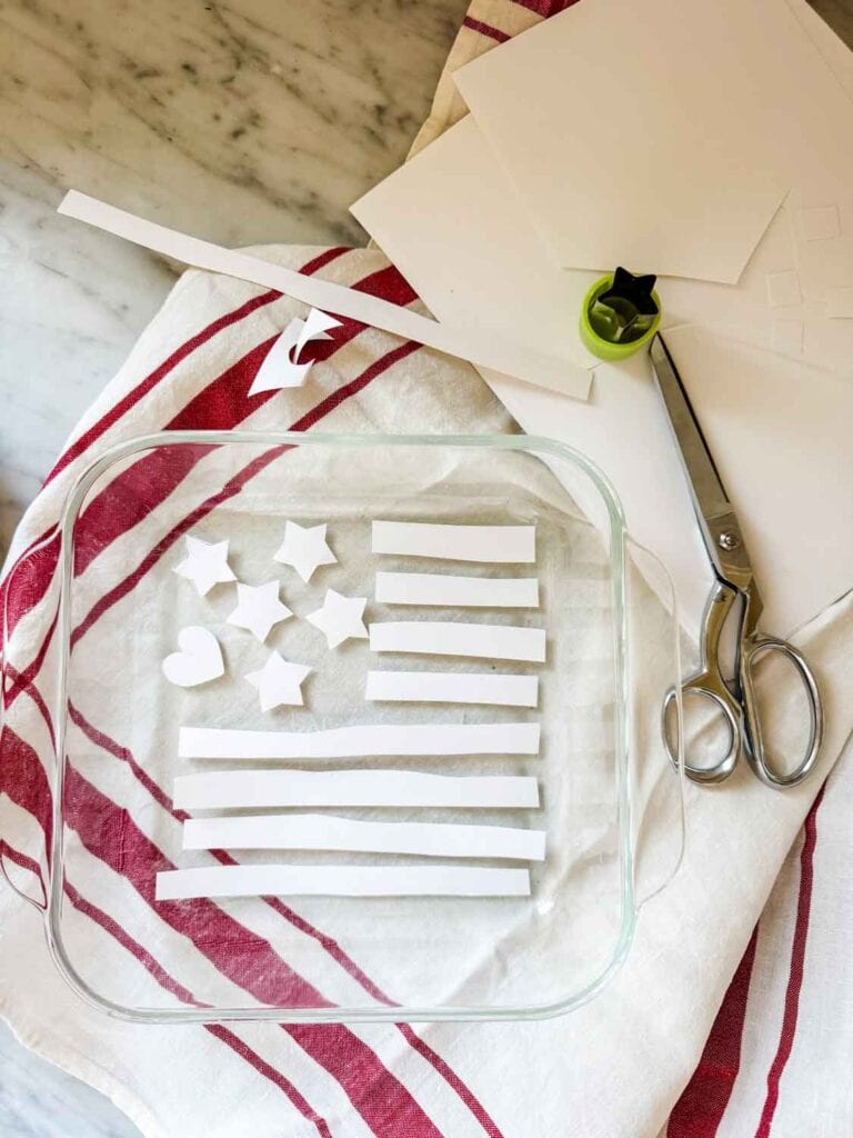 Stars, stripes, and a heart have been cut out of cardstock and will be used for decorating a brownie.