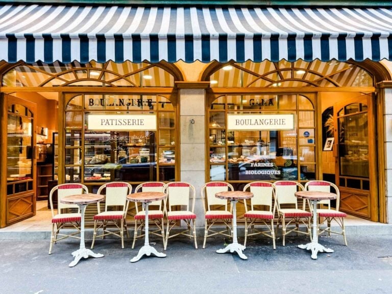 Blue and white striped awning over a boulangerie in Paris. Table and chairs are out front on the sidewalk.