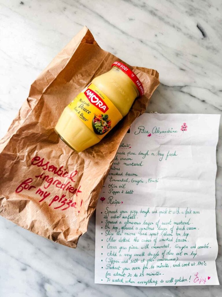 Jar of mustard on crumpled brown paper bag, recipe on white paper.