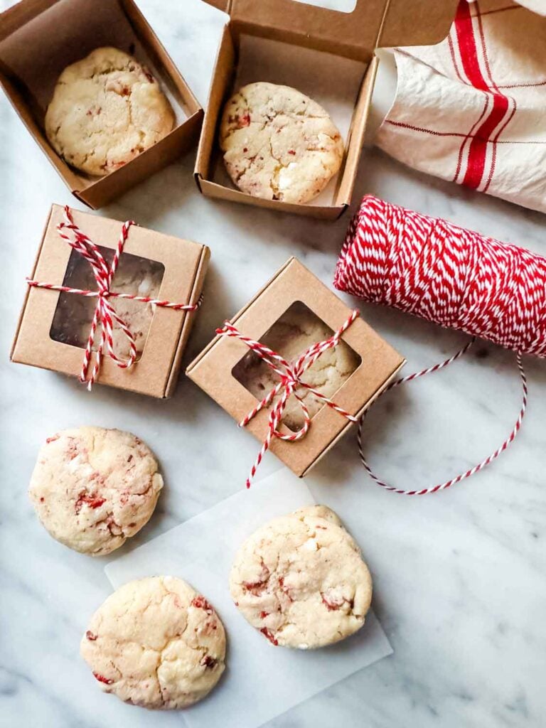 Strawberry cheesecake cookies in tiny kraft paper boxes tied up with red and white bakers' twine.