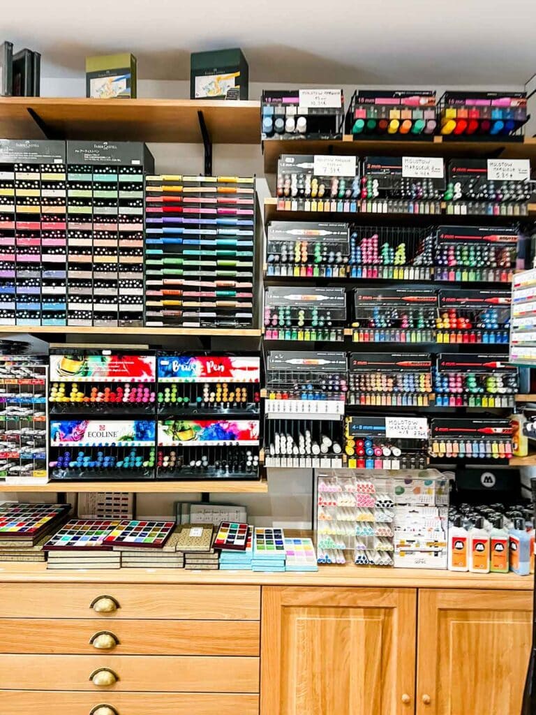 Inks, pens, and paints of all kind line the shelves of this display inside a section of the Sennelier art supply store. 