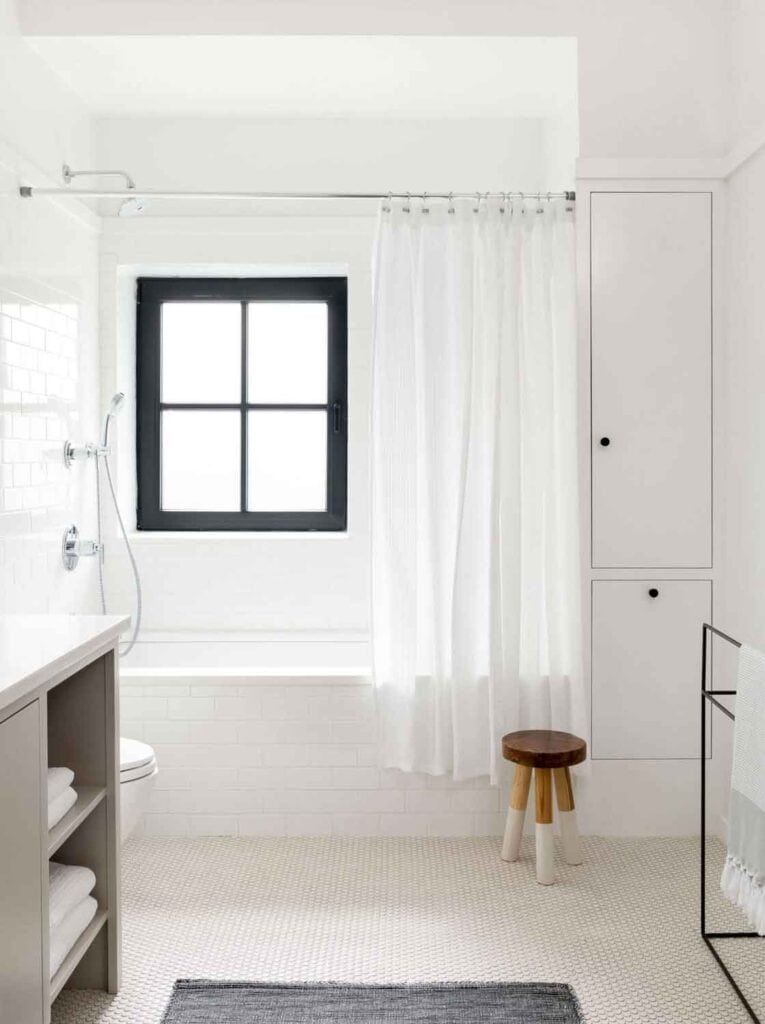 Black and white bathroom with a window, stool.