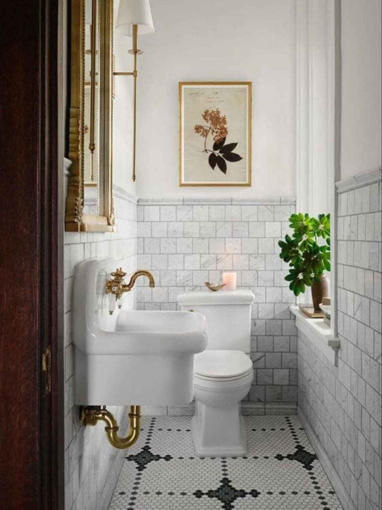 Marble tile, wall mounted vinatge skink with brass fixtures, floral art on wall.