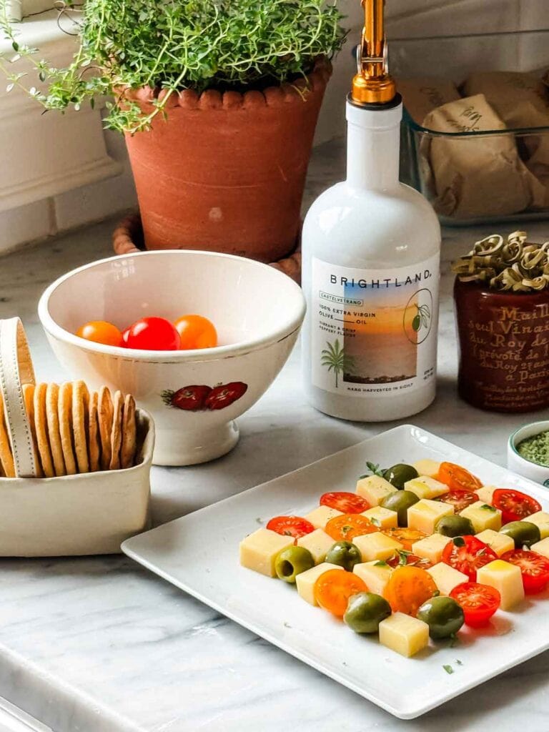 Checkerboard cheese plate, Brightland olive oil, bowl of tomatoes. 