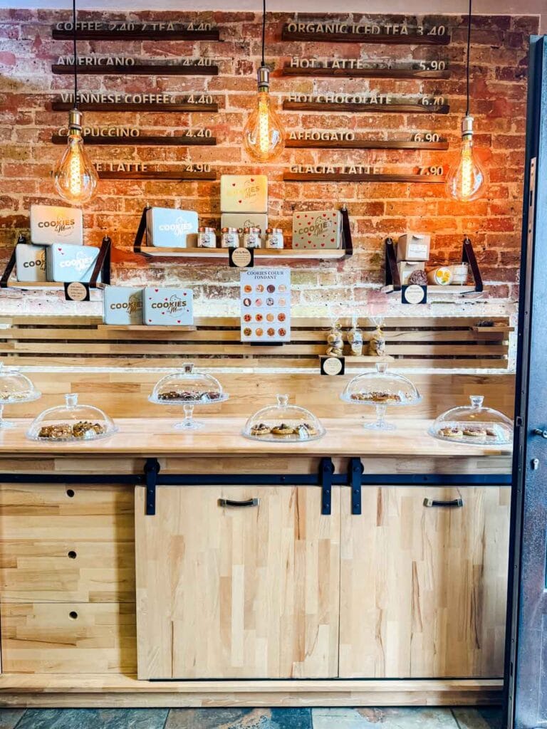 Cookies by Moon's menu sit above a bar lined with glass domes of their artisan cookies.
