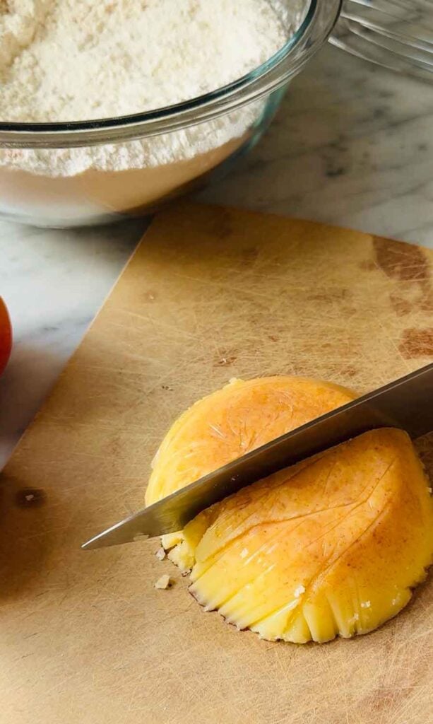 Harden brown butter is being cubed with a sharp knife before it's added to the flour mixture.