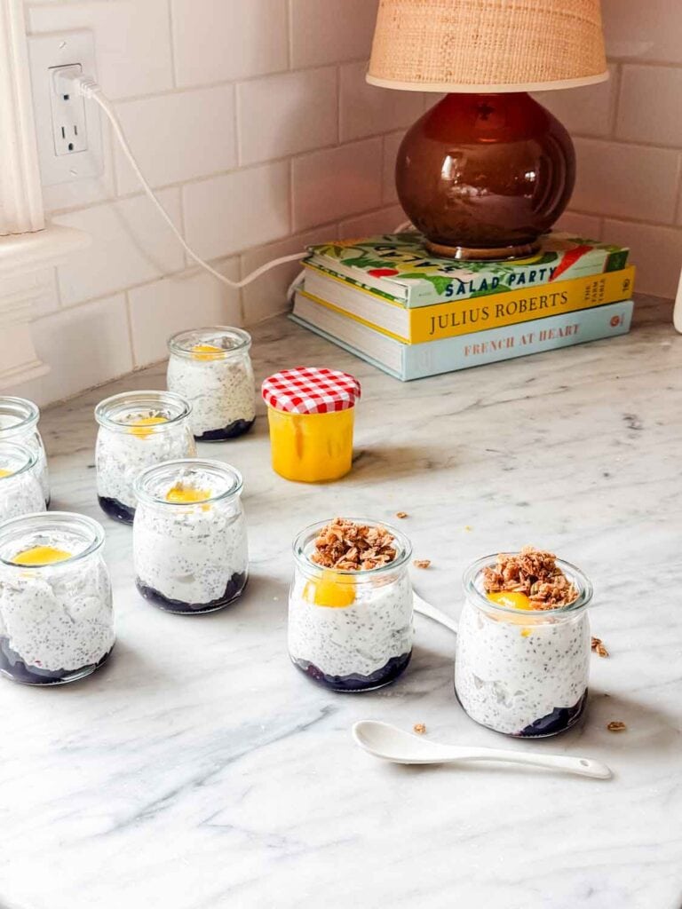 Chia seed pudding, in small jars, are topped with a dollop of lemon curd and two of them are also topped with granola.