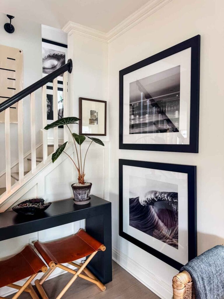 Large black and white photographs of waves, collage art piece, leather camp stools under console table, plant in pot from Denmark.