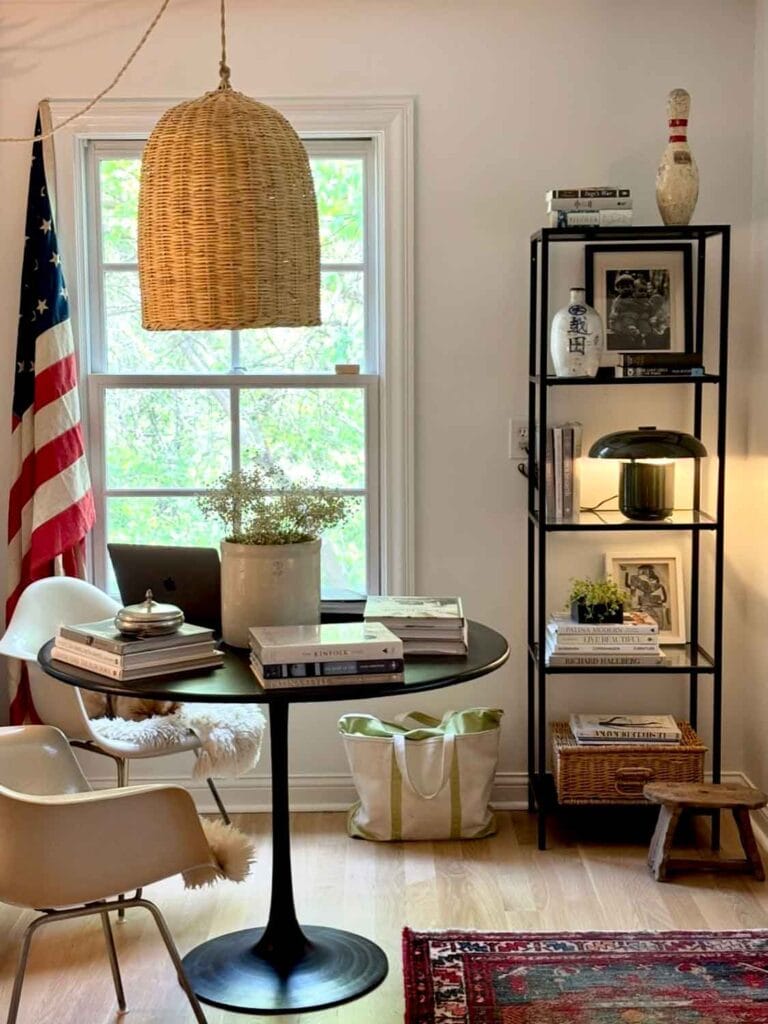 Wicker pendant, modern chair, leather agenda, crock, books, tall shelf with bowling pin. 