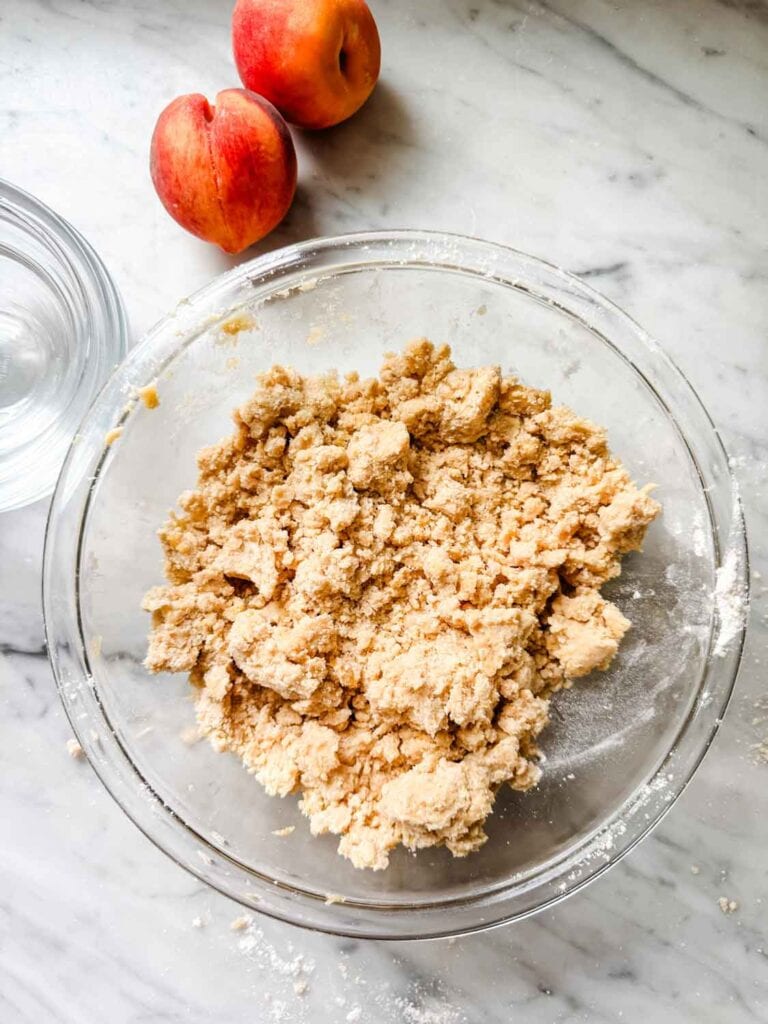 Some of the shortbread dough is saved in a bowl for sprinkling over the peaches.