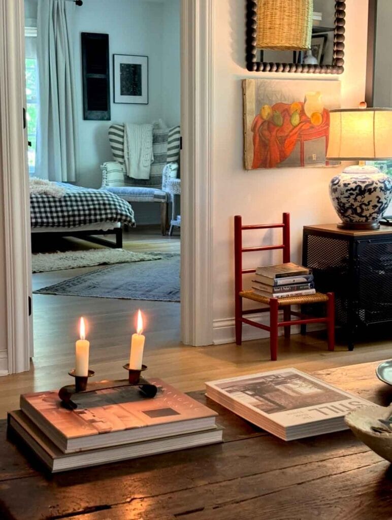 Small red chair with books, gallery wall, candles on table. 