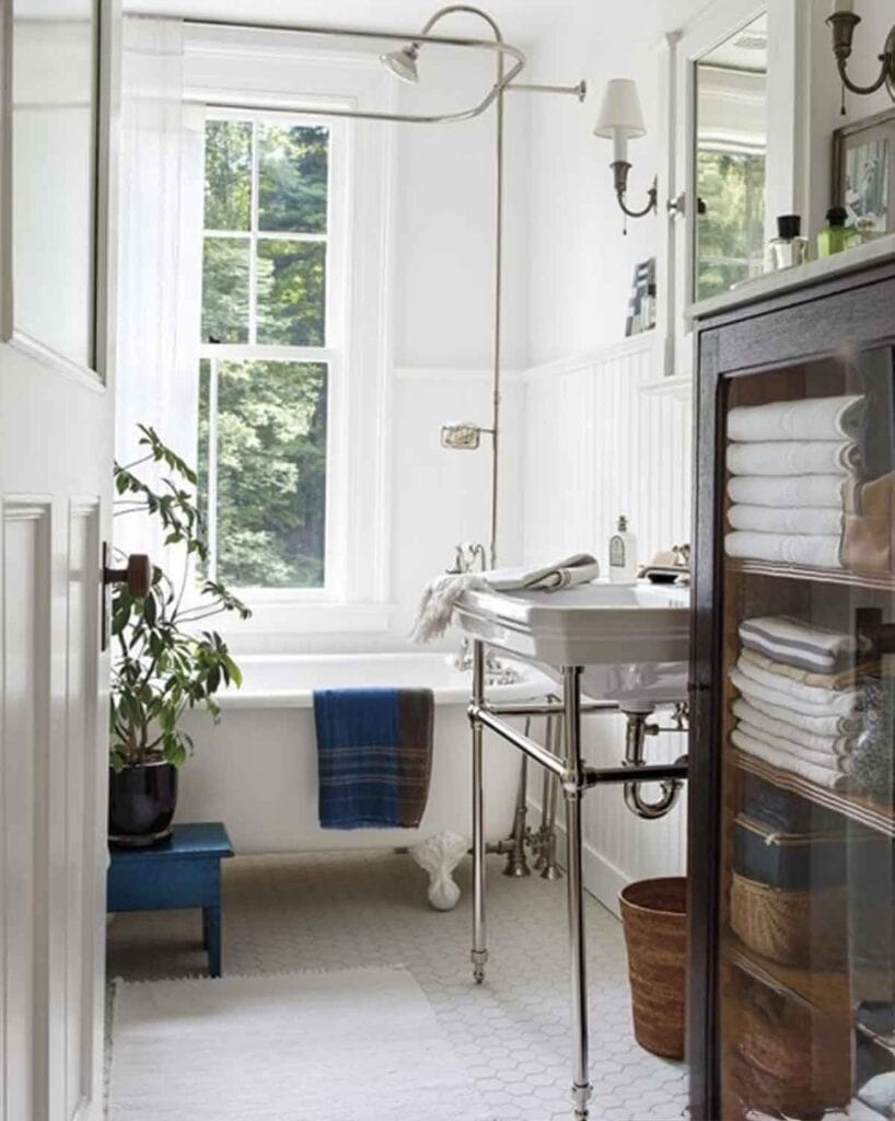 Sink with chrome stand, wood glass front cabinet for towel storage.