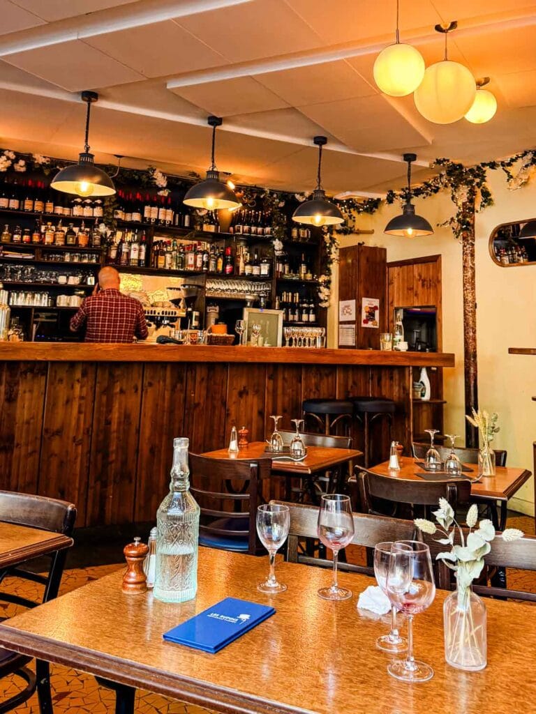 Tables in the foreground and a fully-stocked bar in the background at Les Rupins in Paris.