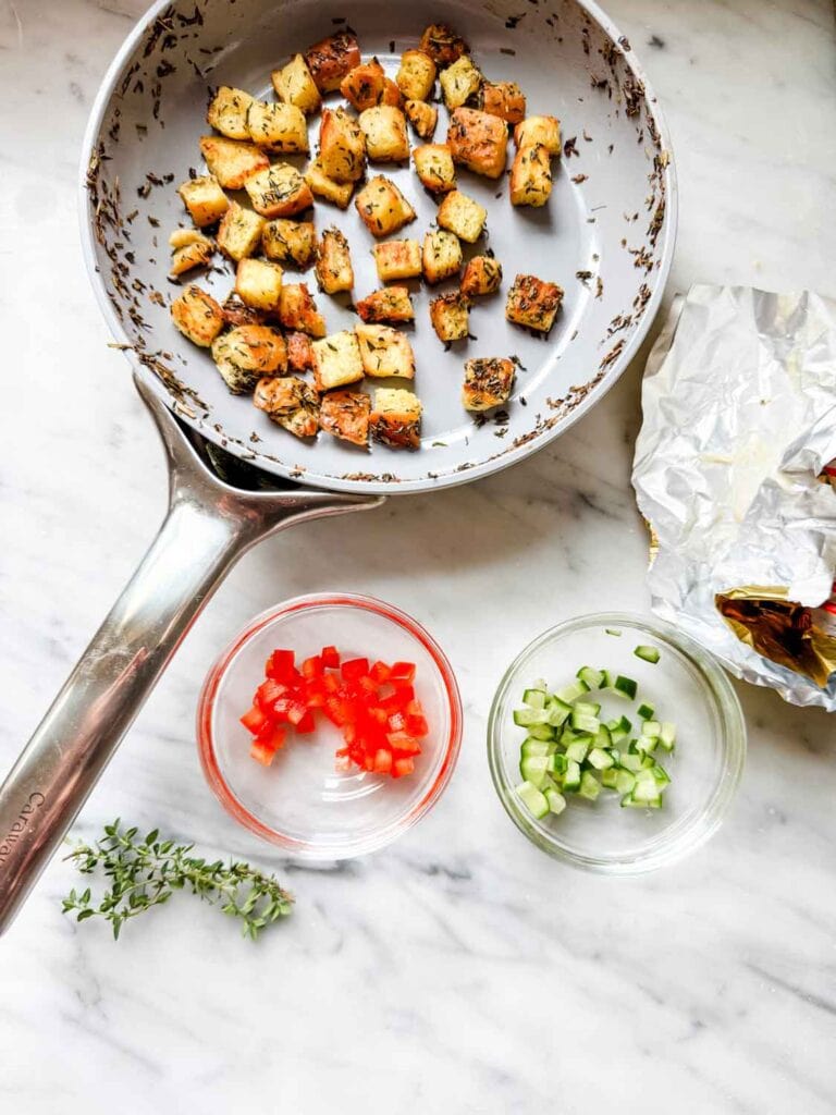 Caraway non-stick skillet with brioche croutons. small dishes of red pepper and cucumbers, thyme.