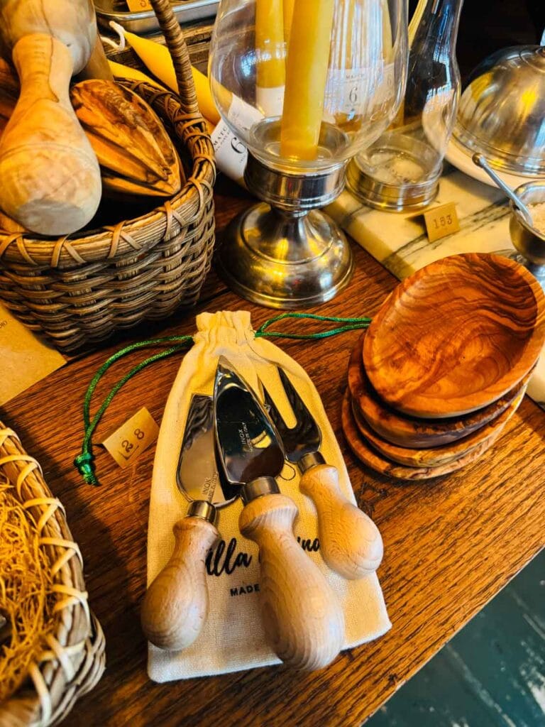 Cheese knives are on table next to olive wood bowls on table inside Officina 1397.