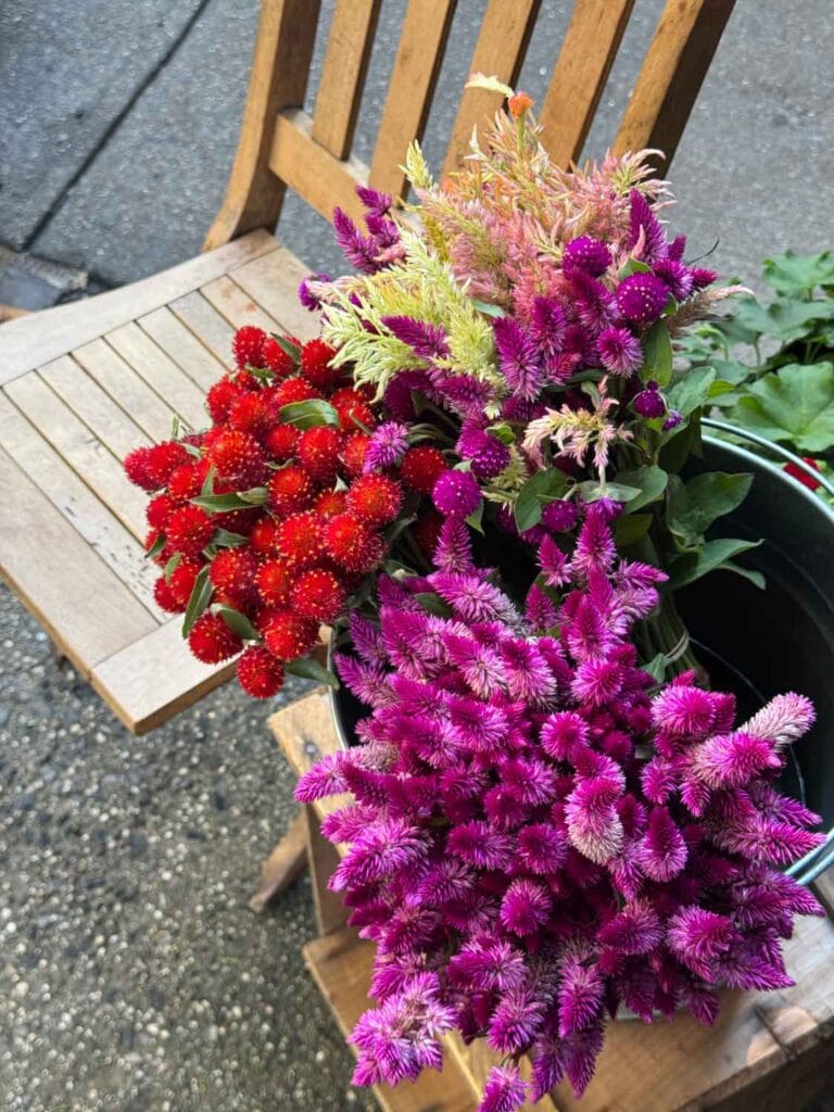 Fresh flowers on a stool next to a vintage wooden chair are on the sidewalk in front of Officina 1397.