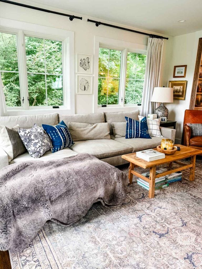 Sectional sofa in front of windows with pillows, lamps. coffee table. 