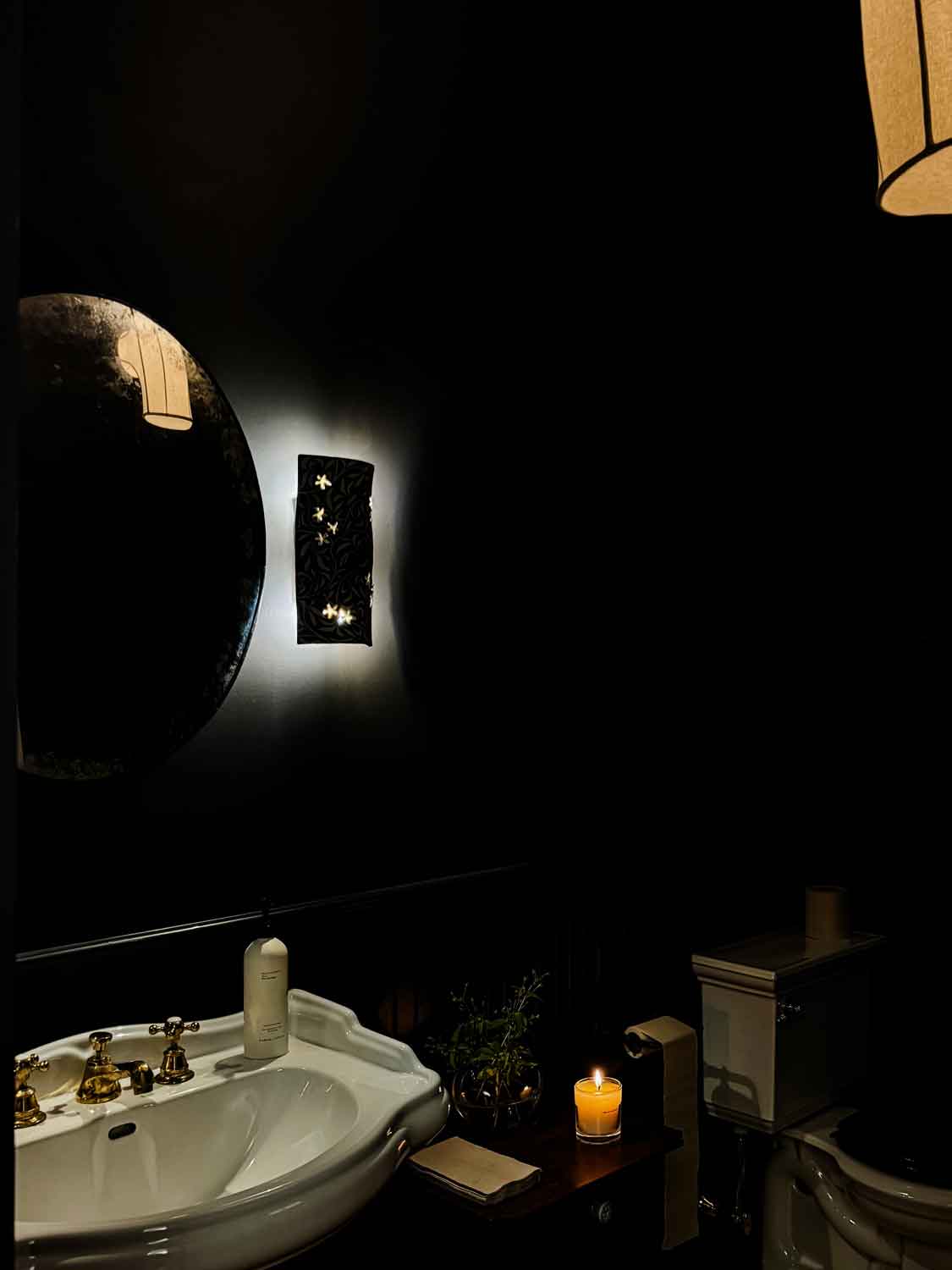 Bathroom with white sink, black walls, candle burning.