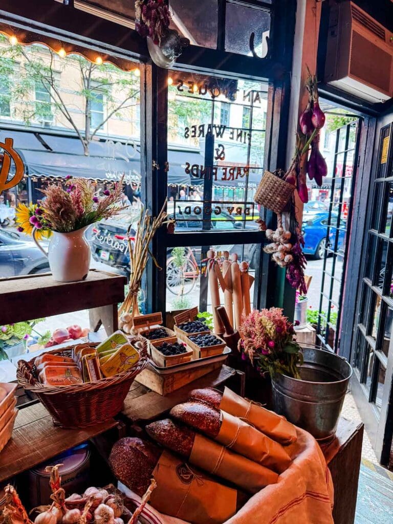 A large basket of fresh bread is next to a crate of garlic cloves on a window display at Officina 1397.