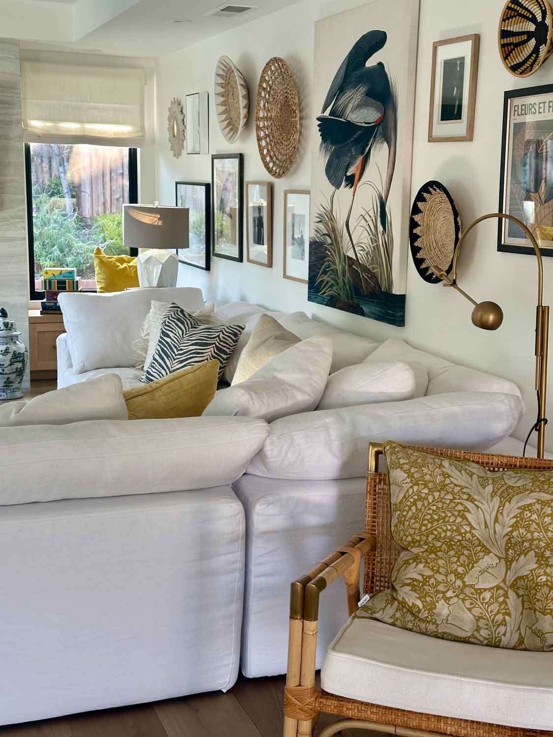 Gallery wall with art and baksets above a white sectional sofa.