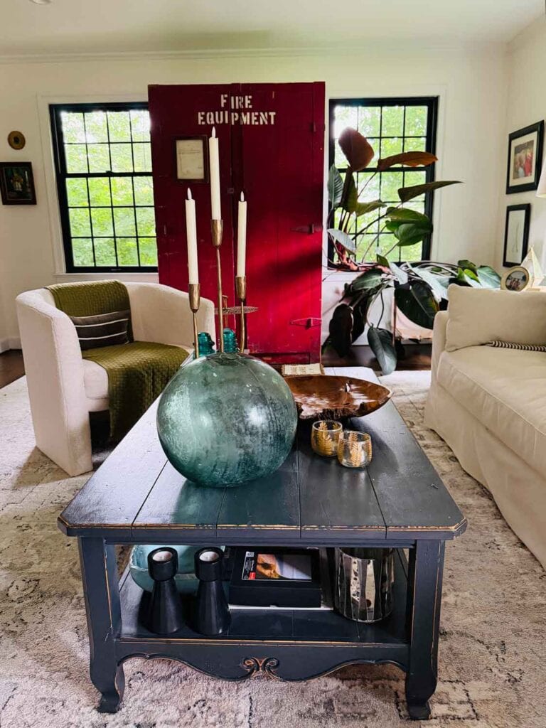 Red fire equipment locker in a living room with glass bottle, black painted coffee table.