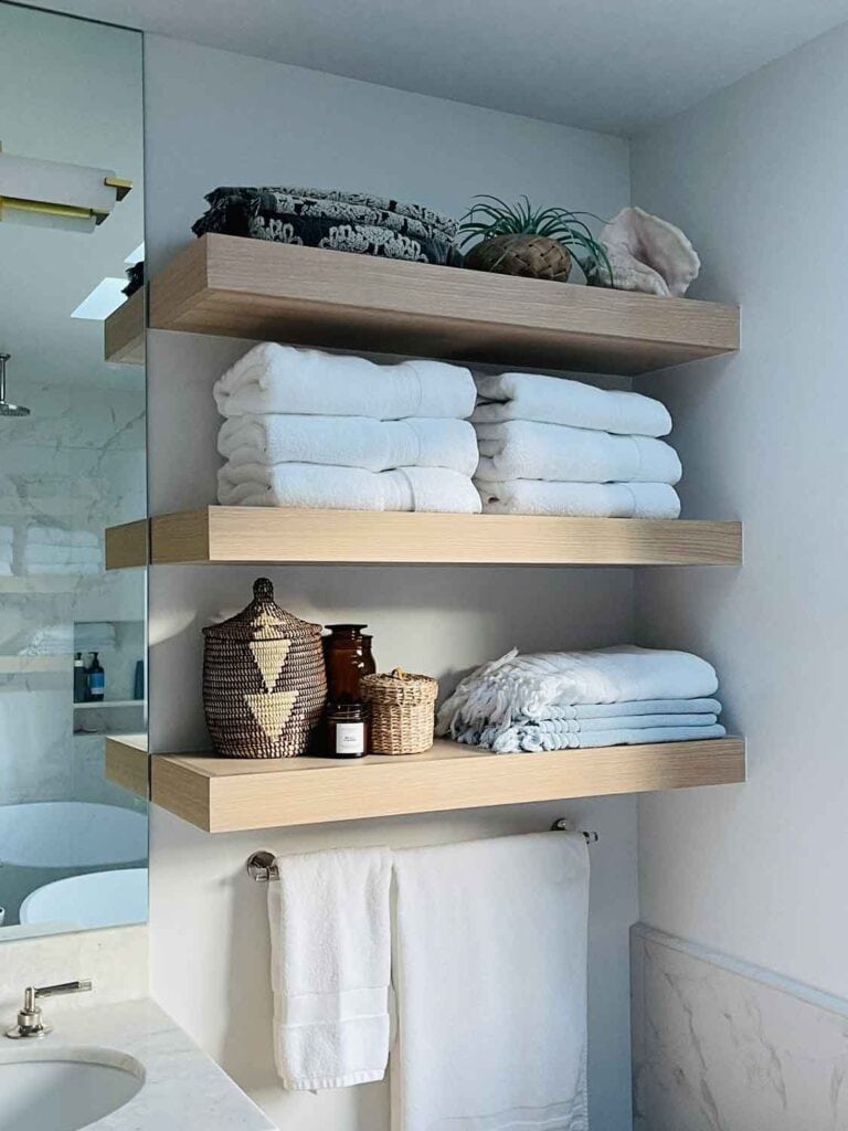 Open shelving in bathroom with white towles, woven cannister,,