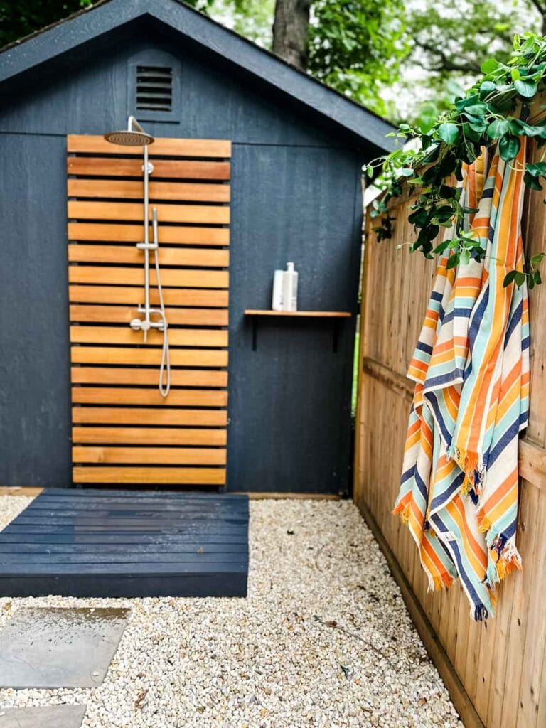 Black and cedar out door shower wiht striped towels.