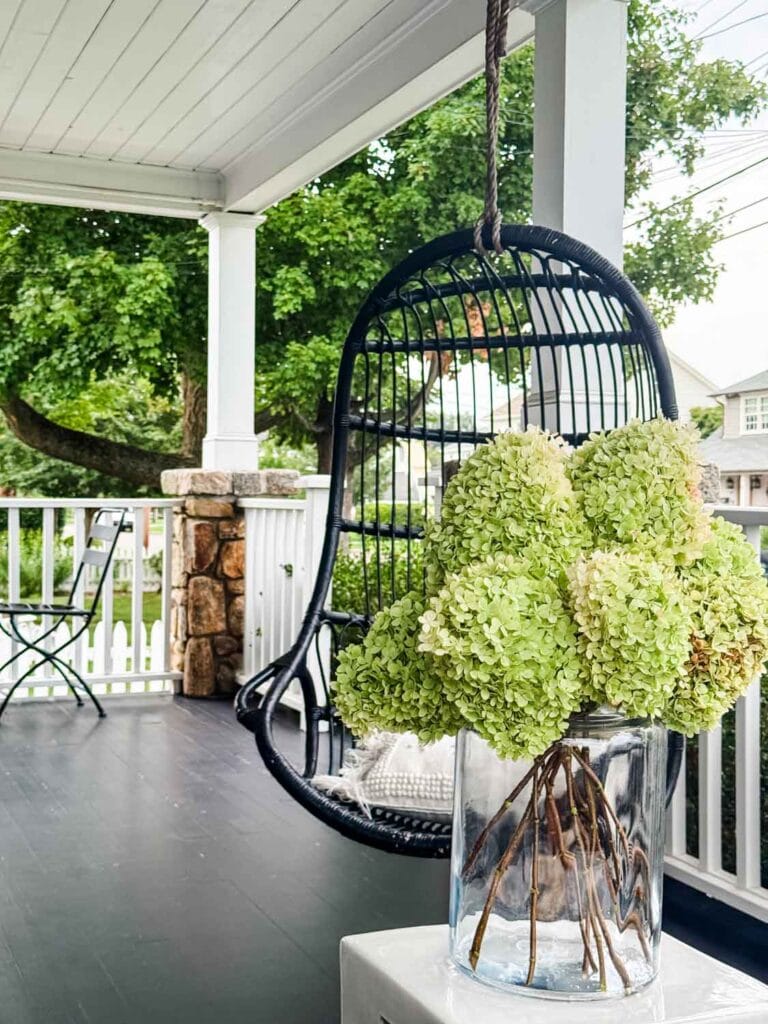 Laqrge glass ar of hydrangeas on a porch.