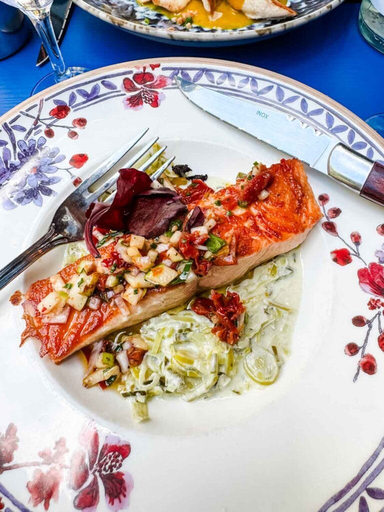 Grilled salmon over a bed of fondue leeks is served on a floral plate at Les Rupins in Paris.