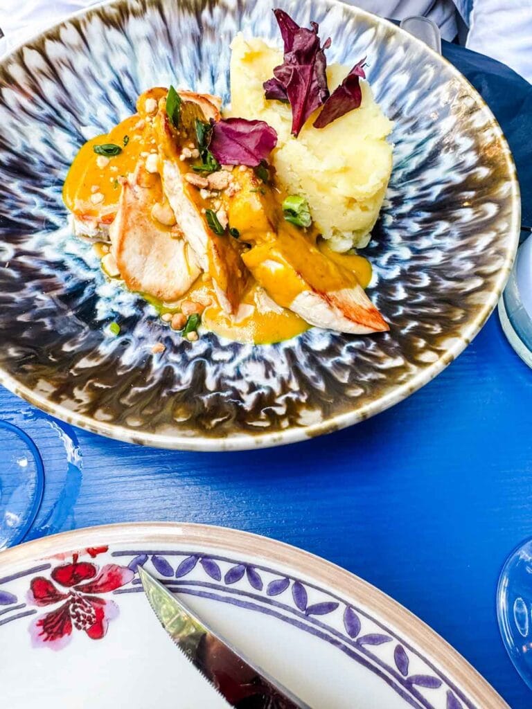 Seared chicken with satay crushed potatoes and garden peas is served on a decorative plate at Les Rupins in Paris.