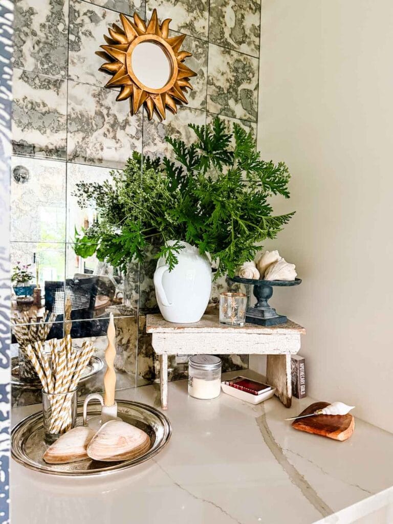 Small stool with greens, shells, straws, candle, mirror.