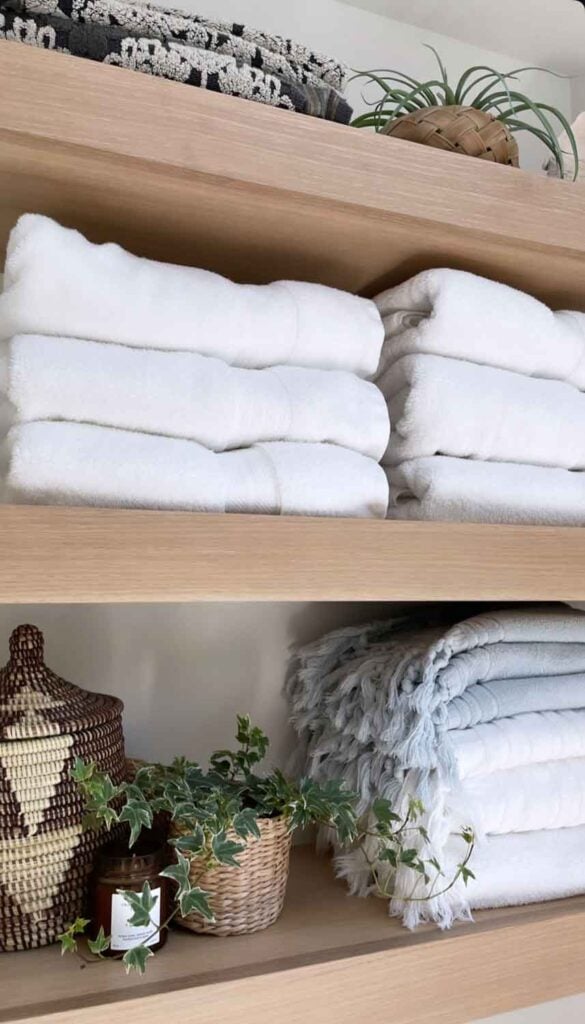 Stacks of white towles, fern in basket.